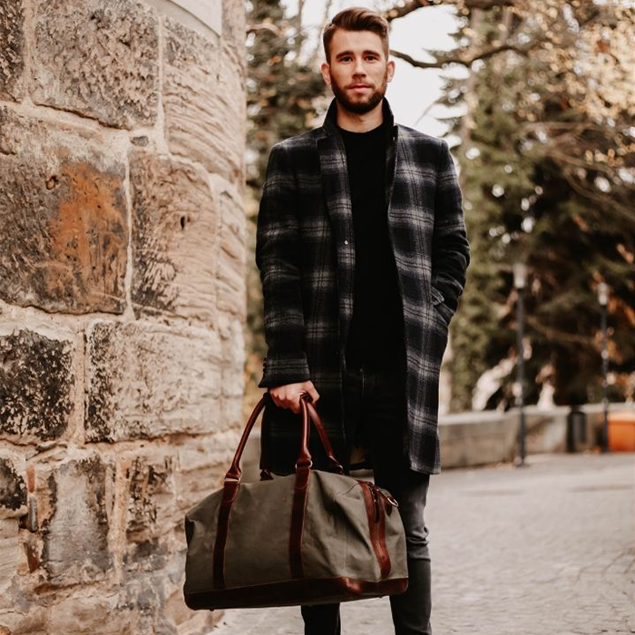 Mann mit hochwertiger Tasche in steht im Park